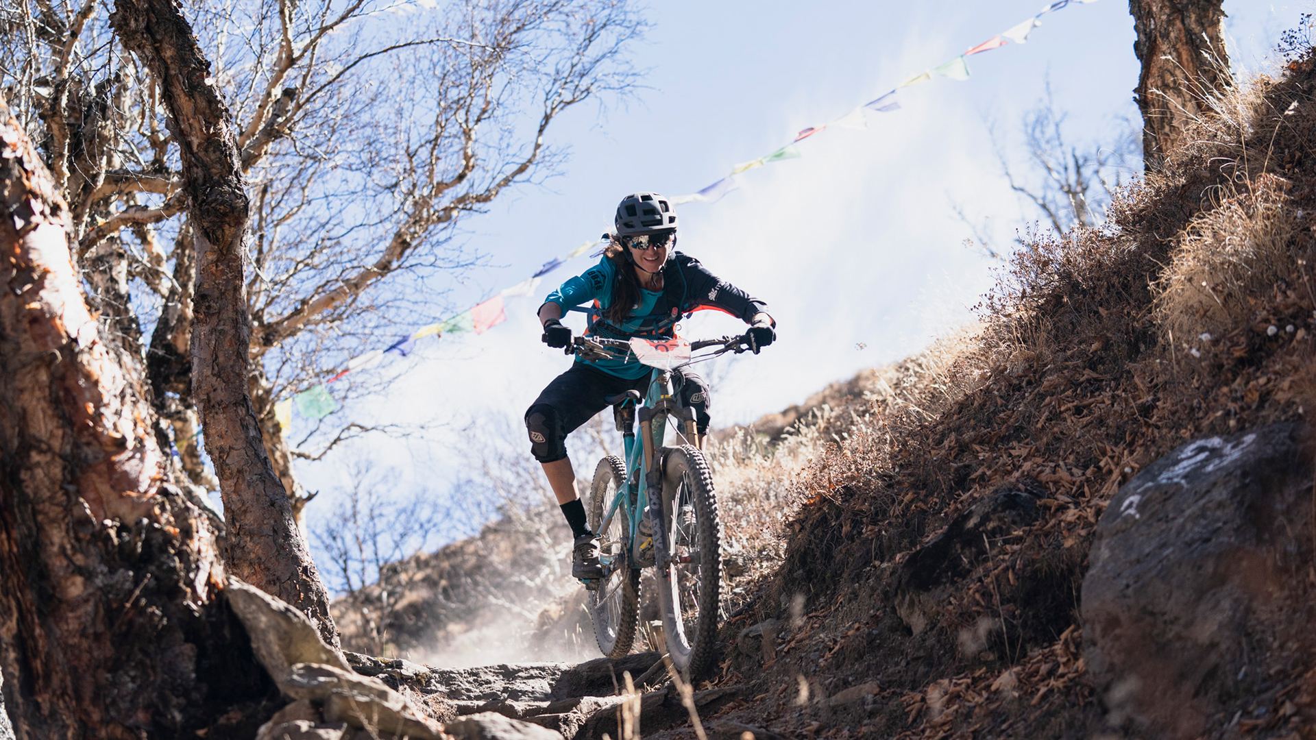 Megan Rose riding beneath prayer flags and bare trees